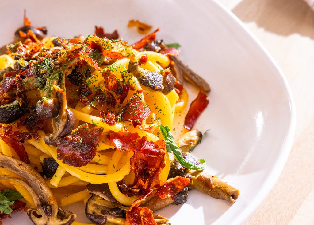 Spaghettoni con crema di zucca, funghi e speck croccante